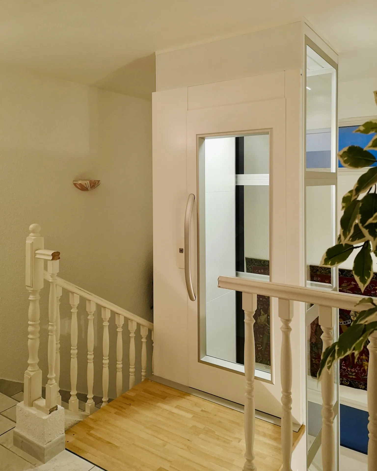 Ascenseur privatif blanc vu depuis le palier avec balustrades en bois